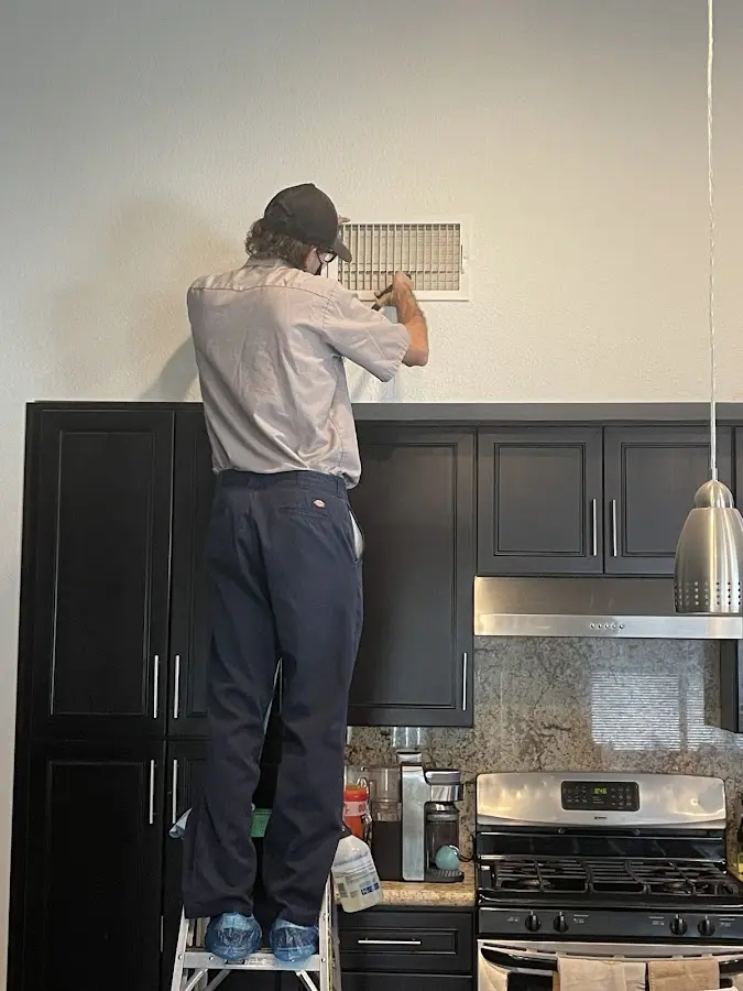 Technician inspecting an air vent during HVAC service in Colville